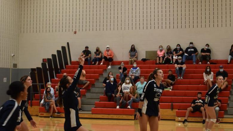 Volleyball players on court during a home match. 